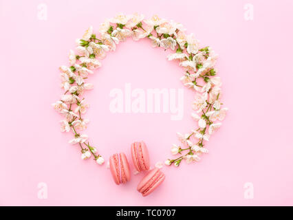 Zusammensetzung mit schönen Blumen und macarons auf farbigen Hintergrund Stockfoto