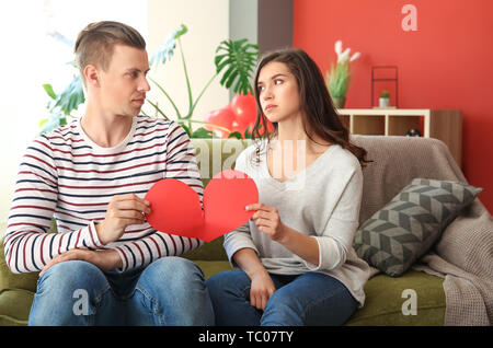 Unglückliche junge Paar zerreißt Papier Herzen zu Hause. Konflikt in Beziehung Stockfoto