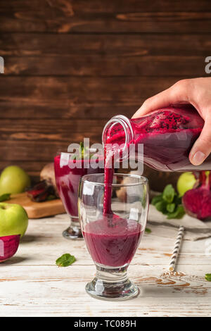 Frau gießen frische Zuckerrüben Smoothie in Glas auf dem Tisch Stockfoto