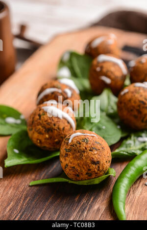 Lecker Falafelkugeln mit Chili und Spinat auf Holzbrett, Nahaufnahme Stockfoto