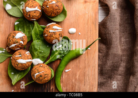 Lecker Falafelkugeln mit Chili und Spinat auf Holzbrett Stockfoto