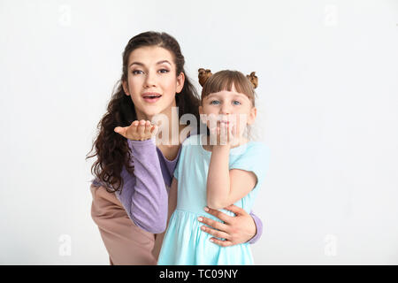Glückliche Mutter mit wenig angenommen Mädchen bläst Kuss auf weißem Hintergrund Stockfoto