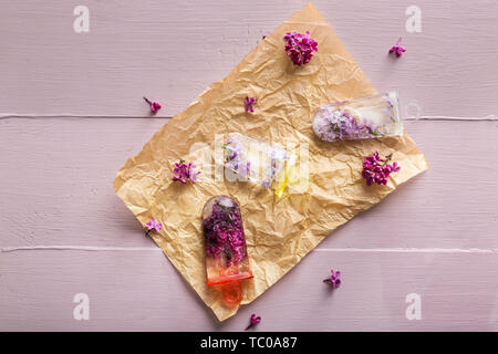 Eis am Stiel mit frischen Blumen lila Blumen auf hölzernen Tisch Stockfoto