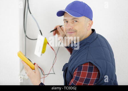 Elektriker die Messung der Spannung der Kabel an der Decke im Innenbereich Stockfoto