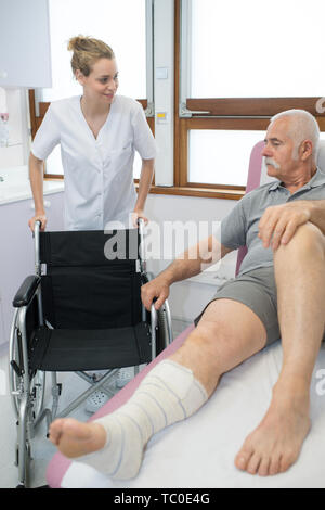 Krankenschwester bei einem Patienten auf dem Weg zu seinem Rollstuhl Stockfoto