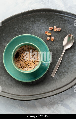 Eine Tasse schwarzen Kaffee, geschossen von oben auf einem Tablett mit karamellisierten Zucker und einem Löffel Stockfoto