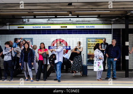 Menschen stehen und für einen Zug auf der Plattform in der Sloane Square London U-Bahnstation warten Stockfoto