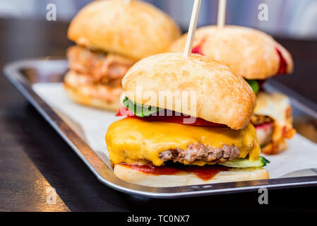 Schließen Sie bis zu drei leckere Burger mit unterschiedlicher Füllung auf Tablett serviert. Stockfoto