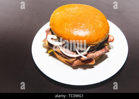 Leckere hausgemachte Butter Roastbeef Burger mit knusprigen Brötchen mit Onio Stockfoto