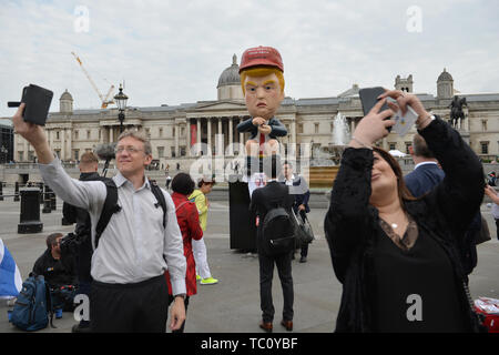 Pendler und Touristen nehmen selfies mit einem 16 ft Roboter sprechen von US-Präsident Donald Trump sitzen auf einem gold wc auf dem Trafalgar Square, London Am zweiten Tag des Staatsbesuchs in Großbritannien durch US-Präsident Donald Trump. Stockfoto