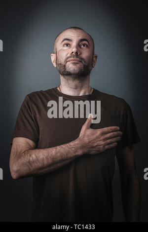 Zufrieden und Stolz, Mann mit seiner Hand über sein Herz posieren. Studio Portrait. Stockfoto