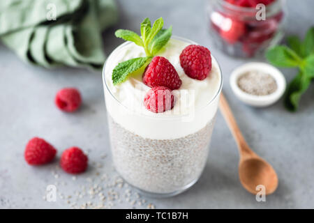 Vegetarische Chia Pudding mit Himbeeren und griechischer Joghurt Schicht. Grauer Beton Hintergrund Stockfoto