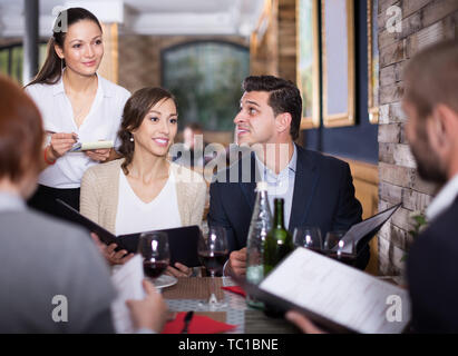 Mitarbeiter Kellnerin weibliche, um von positiven Besucher im Restaurant Stockfoto