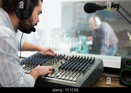 Toningenieur bei Mischen Panel im Radio Studio, Controlling Niveau und die Qualität des Klangs auf der Luft arbeiten Bärtigen Stockfoto