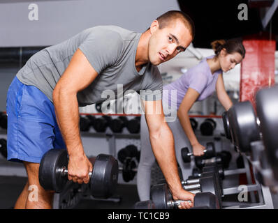 Sportliche Menschen unter schweren Sport Hantel auf dem Regal im Fitnessstudio Stockfoto