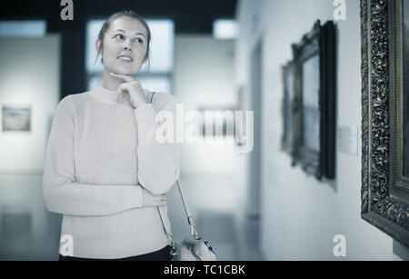 Porträt der jungen Frau, die in der Nähe der Malerei in Baguette in einer Art Museum Stockfoto