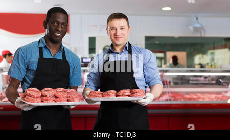 Zwei professionelle Metzger in Metzgerei stehend mit Fächer von frischen, rohen Fleisch Schnitzel Stockfoto