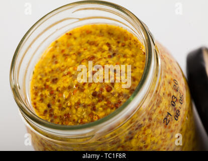 Nahaufnahme des aromatisiert feine Vollkorn Senf Sauce im Glas auf weißem Hintergrund Stockfoto