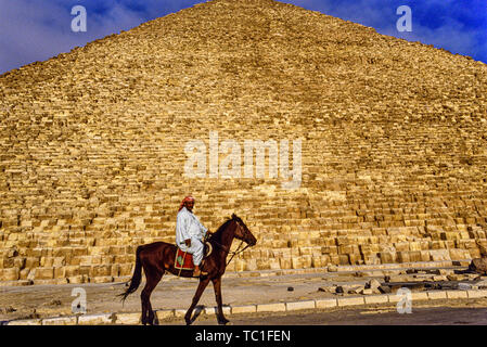 Foto: © Simon Grosset. Die Giza Pyramiden komplex, oder in der Nähe der Nekropole von Gizeh, Kairo, Ägypten. Ein Mann reitet ein Pferd vor der Großen Pyramide von Gizeh, o Stockfoto