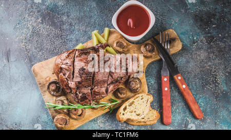 Gebackene Lamm mit Pilzen und Gewürzen und Kräutern auf einem konkreten Hintergrund. Halal Fleisch und Lebensmittel Stockfoto