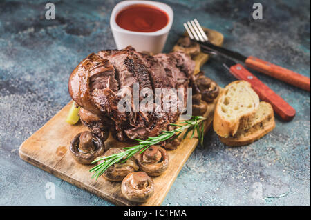 Gebackene Lamm mit Pilzen und Gewürzen und Kräutern auf einem konkreten Hintergrund. Halal Fleisch und Lebensmittel Stockfoto