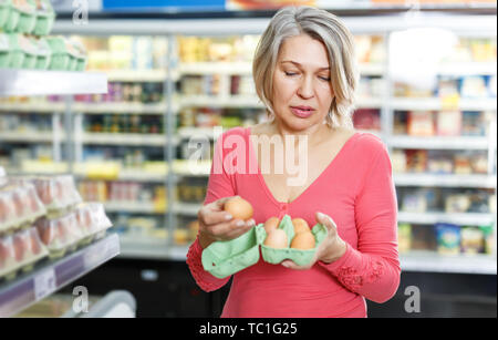 Portrait von Casual ältere Frau, die Einkaufen für Eier in Essen Abteilung der Supermarkt Stockfoto