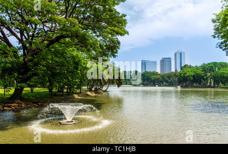 Ein Teich mit Springbrunnen, Blick auf Bangkok Wolkenkratzer vom Lumpini Park, grüne Oase in der modernen Stadt, Thailand Stockfoto