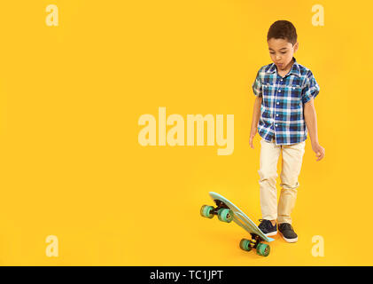 Portrait von niedlichen kleinen Jungen mit Skateboard auf farbigen Hintergrund Stockfoto