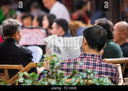 Mann liest Zeitung in Chengdu Menschen Park Stockfoto