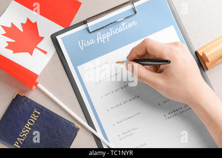 Frau ausfüllen Visa Application Form am Tisch. Konzept der Einwanderung Stockfoto