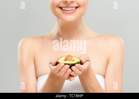 7/8-Ansicht fröhliche Frau mit der Hälfte der reife Avocado isoliert auf Grau Stockfoto