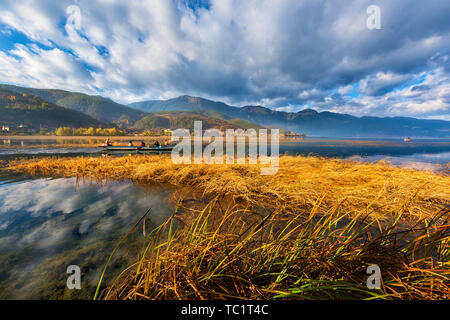 Lugu See im Herbst, satter Farbe in die Ruhe, die mit transparentem Boden See von Zeit zu Zeit die Mosuo Mensch - Schwein trog Boot überqueren. Stockfoto