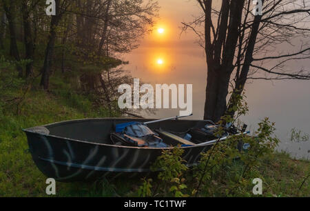 Die Sonne beginnt über ein altes Fischerboot am Ufer der Wildnis See im nördlichen Wisconsin ruhen zu steigen. Stockfoto