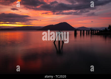 Einen traumhaften Sonnenuntergang über den flachen ruhiges Wasser an der Küste von Wrangell, Alaska, der Himmel scheint auf Feuer und die schöne rosa, rot zu werden und Stockfoto