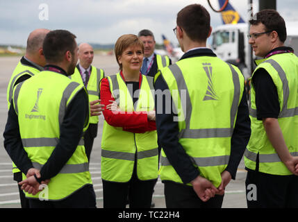 Die erste Ministerin Nicola Sturgeon spricht auf der Asphaltbahn am Flughafen Edinburgh mit Auszubildenden, als sie offiziell eine Terminalerweiterung eröffnet. Millionen £80 wurden in den Ausbau des Terminals investiert, der neue internationale und nationale Ankunftshallen und Gepäckabgabebereiche, neue Gates und Sitzbereiche, neue Flugzeugstände, neue Lounges und neue Einzelhandelsgeschäfte sowie Lebensmittel- und Getränkestände bietet. Stockfoto