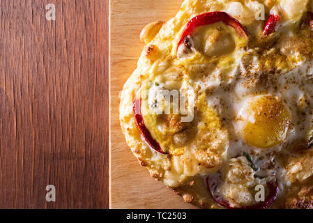 Gebackenes Ei mit Käse und Gemüse auf Brot auf einem Holzbrett. Kopieren Sie Platz Stockfoto