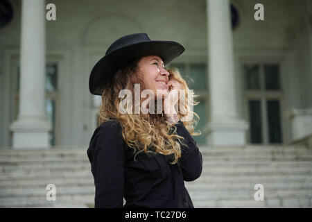 Modische Mädchen in schwarzen T-Shirt, Hut und eine weite Hose in der Nähe von Old White House posing gekleidet Stockfoto