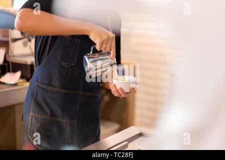 Barista Hand gießen Milch, latte Art Kaffee im Cafe. Stockfoto