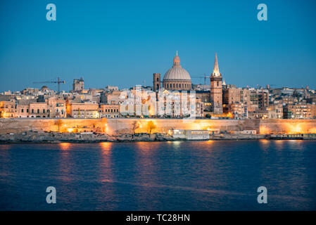 Blick auf Valletta Skyline am schönen Sonnenuntergang von Sliema mit Kirchen Unserer Lieben Frau auf dem Berg Karmel und St. Paul's Anglican Pro-Cathedral, Va Stockfoto