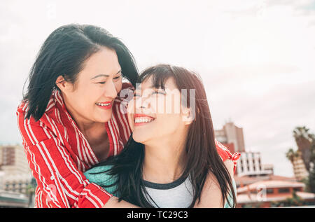 Glückliche Mutter und Tochter Spaß im Freien - asiatische Familie genießen die Zeit zusammen außerhalb - Begriff des Menschen Lifestyle, der Liebe und der Elternschaft Stockfoto