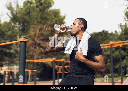 Sportliche Menschen Trinkwasser Nach dem Training am Sportplatz Stockfoto