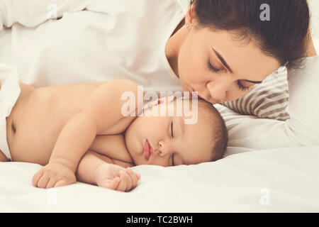 Mutter küssen ihr neugeborenes Baby im Bett schlafen