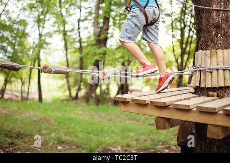 Junge Junge, die Kabel unter den Bäumen, extreme Sport im Adventure Park Stockfoto