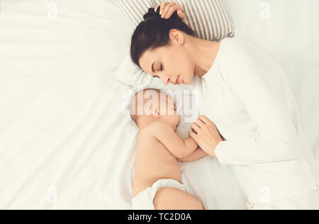 Junge Mutter und ihr Baby schlafen im Bett Stockfoto