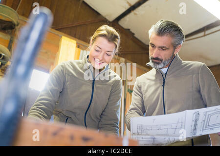 Männliche und weibliche Arbeitnehmer mit Blick auf Pläne in der Werkstatt Stockfoto