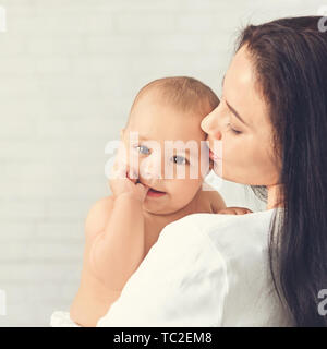 Mutter küssen Kind, Baby ruht auf Mom Schulter Stockfoto