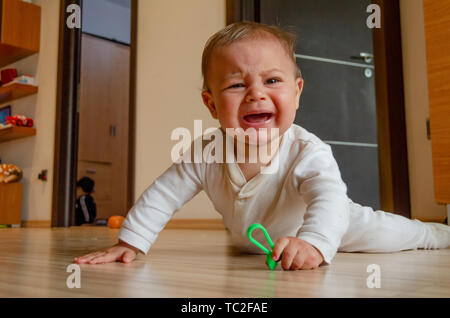 Cute sechs Monate alten Baby boy in Bauch auf den Boden und schreien nach Aufmerksamkeit Stockfoto