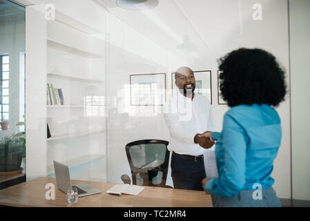 Manager stehen in seinem Büro Händeschütteln mit einem Mitarbeiter Stockfoto