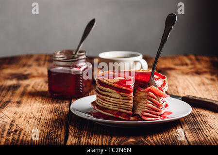 Stapel von amerikanischen Pfannkuchen mit roten Beeren Marmelade auf der Platte über rustikale Oberfläche Stockfoto