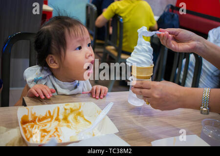 CHIANGMAI, THAILAND - Mai 3,2019: Kleines Kind essen Eis schreien im Hintergrund von KFC (Kentucky Fried Chicken) Stockfoto